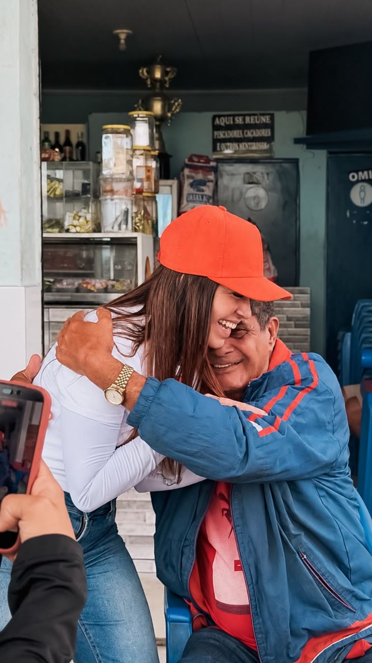 Morador abraça Kelaine, os dois rindo
